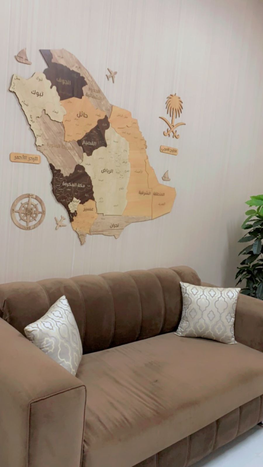 Decorative map on a wall above a brown sofa with white cushions.