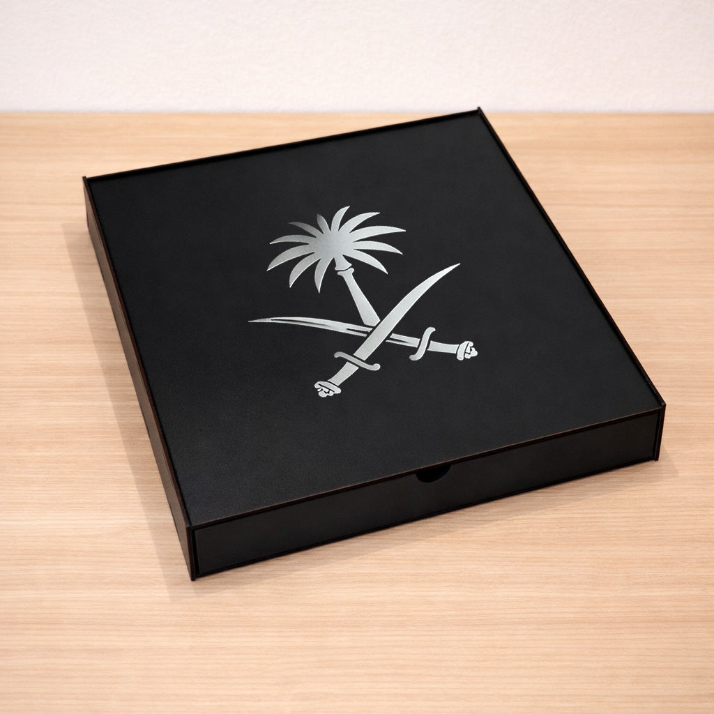 Black box with a silver Saudi Arabia national Symbol on a wooden surface