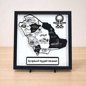 Framed map of Saudi Arabia with black and white design on a wooden surface.